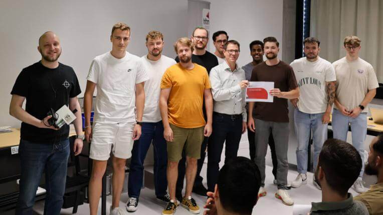 Die Gewinnergruppe von Studierenden steht gemeinsam und hält den Preis