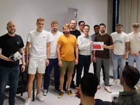 Die Gewinnergruppe von Studierenden steht gemeinsam und hält den Preis