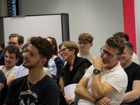 Publikum aus der Nähe, Menschen sitzen dicht beieinander und hören aufmerksam zu.